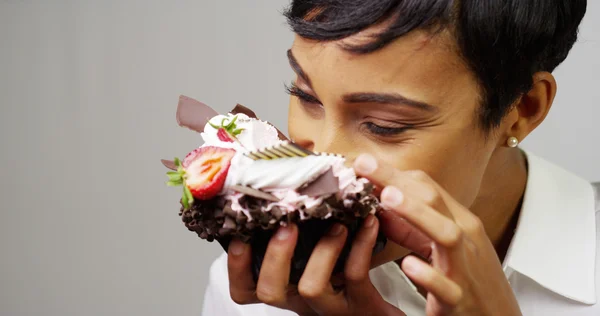 Черная женщина делает беспорядок, поедая огромный модный десерт — стоковое фото