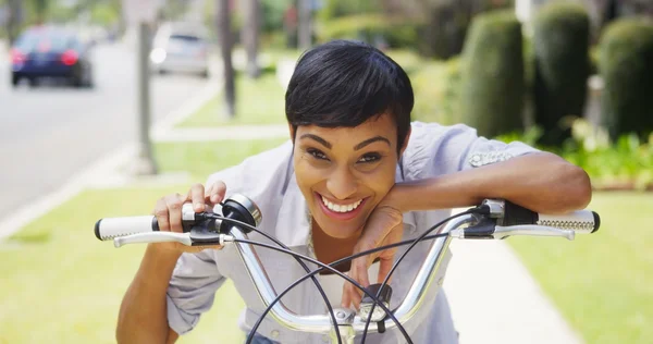 Mulher negra tocando sino de bicicleta e sorrindo ao ar livre — Fotografia de Stock