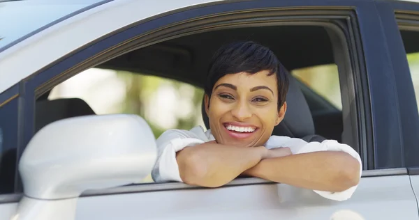 Siyah kadın gülümseyerek ve araba pencereden dışarı bakıyor — Stok fotoğraf