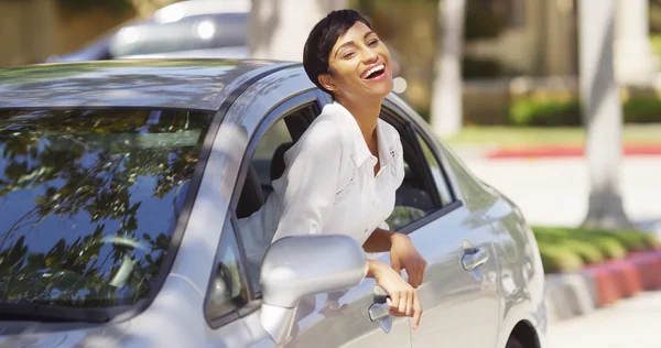 Happy black woman leaning out car window with hands in the air — Stock Photo, Image