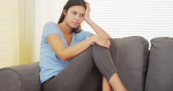 Mujer hispana sentada en un sofá pensando — Foto de Stock