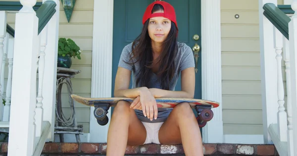 Junge Frau sitzt mit Skateboard auf Veranda — Stockfoto