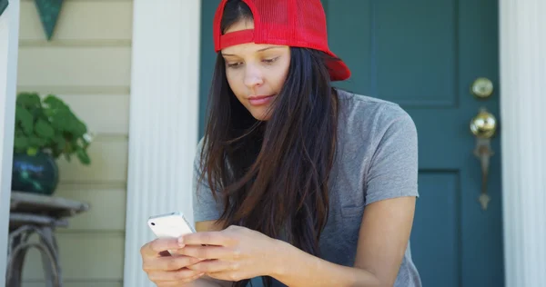 Gelukkig gemengd ras vrouw texting op telefoon op veranda — Stockfoto