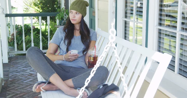 Jonge vrouw texting en zittend op de veranda — Stockfoto