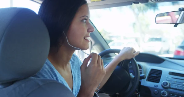 Mixed race woman talking in the car with earphones — Stock Photo, Image