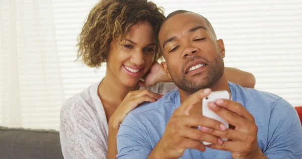 Girlfriend watching over boyfriend's shoulder as he texts — Stock Photo, Image