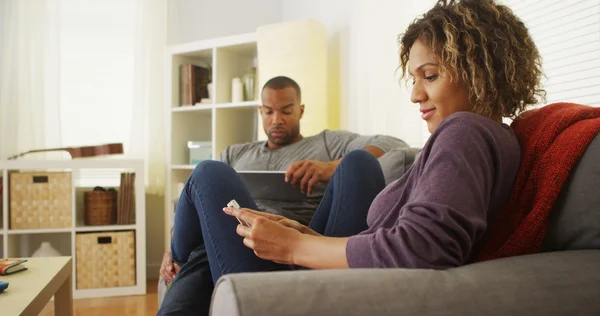 Pareja negra usando dispositivos electrónicos en el sofá — Foto de Stock