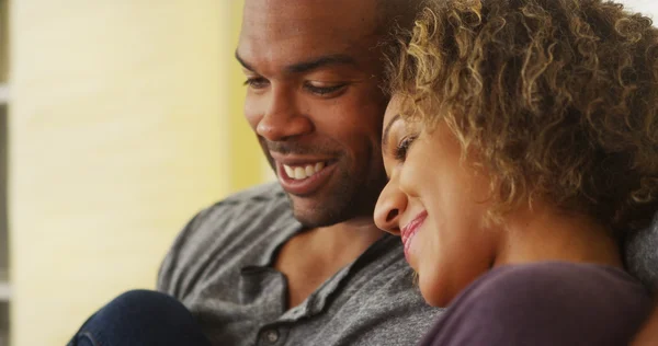 Pareja negra sentada en el sofá sonriendo — Foto de Stock