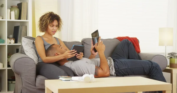 Pareja negra usando sus tabletas en el sofá — Foto de Stock