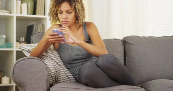 Mulher negra usando smartphone no sofá — Fotografia de Stock