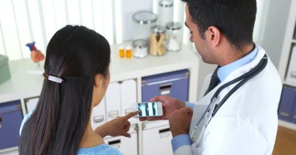 Médico mexicano usando smartphone para mostrar raio-x ao paciente — Fotografia de Stock