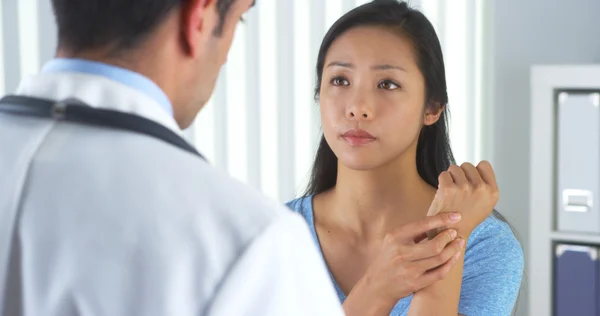 Paciente asiático descrevendo dor de pulso ao médico — Fotografia de Stock