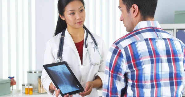 Médico chino repasando rayos X con paciente — Foto de Stock