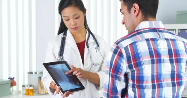 Médico chino repasando rayos X con paciente — Foto de Stock