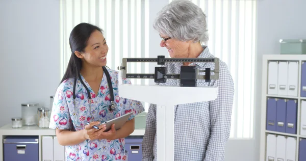 Chinese nurse weighing elderly patient — Stock Photo, Image