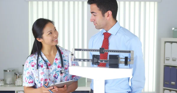 Chinese nurse weighing Mexican patient — Stock Photo, Image