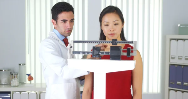 Mexican doctor weighing Chinese patient — Stock Photo, Image