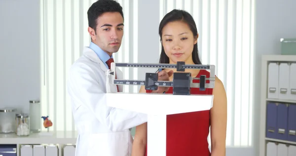 Happy Chinese patient being weighed on scales — Stock Photo, Image