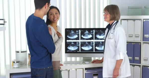 Senior doctor tells interracial couple about pregnancy — Stock Photo, Image