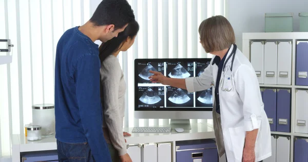 Senior doctor tells interracial couple about pregnancy — Stock Photo, Image