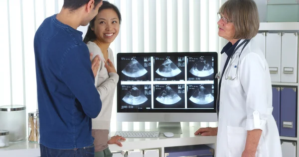 Médico sênior fala com casal interracial sobre exames de gravidez — Fotografia de Stock