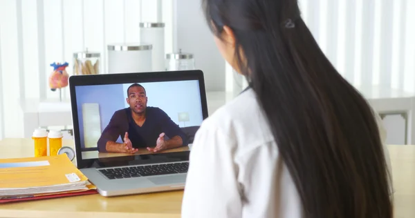 Asian doctor video chatting with African patient — Stock Photo, Image