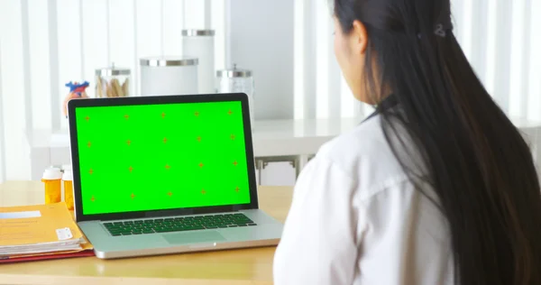 Chinese doctor talking to laptop with green screen — Stock Photo, Image