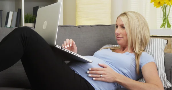 Piękna kobieta w ciąży za pomocą komputera na kanapie — Zdjęcie stockowe