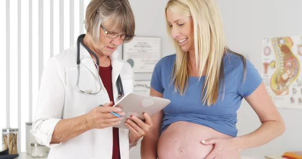 Doctor talking to pregnant woman with tablet — Stock Photo, Image