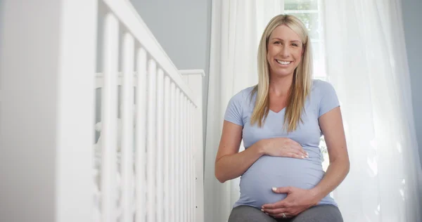 Mooie zwangere vrouw zitten in de kwekerij — Stockfoto