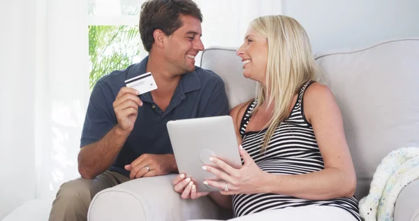 Excited parents smiling at camera with credit card — Stock Photo, Image