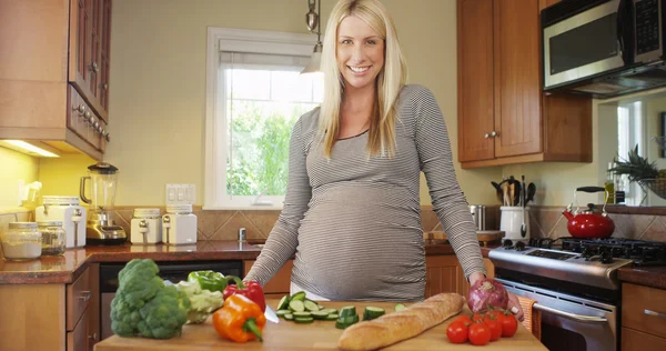 Mujer embarazada sonriendo en la cocina —  Fotos de Stock