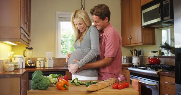 Lyckliga gravida par i köket — Stockfoto