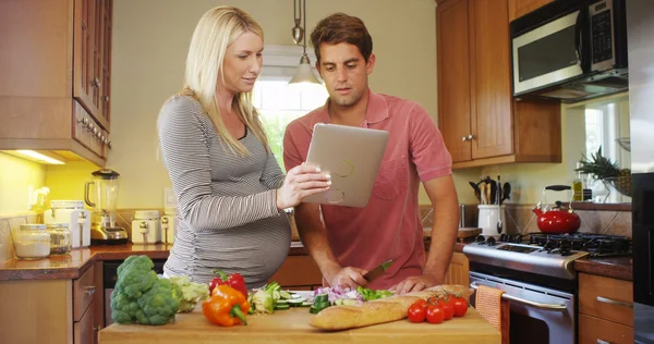 Felice coppia incinta che lavora insieme in cucina — Foto Stock