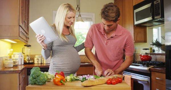 Felice coppia incinta che lavora insieme in cucina — Foto Stock