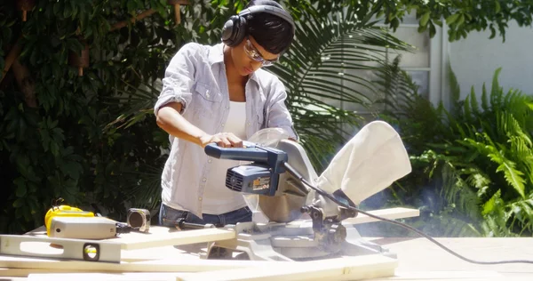 Black woman doing home improvement cutting wood with a table saw — Stock Photo, Image