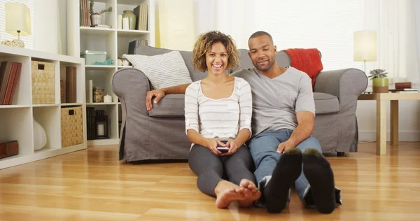 Cute African couple sitting on floor in living room — Stock Photo, Image