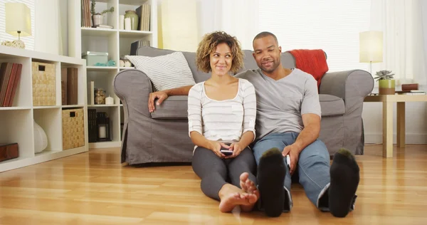 Cute African couple sitting on floor in living room — Stock Photo, Image