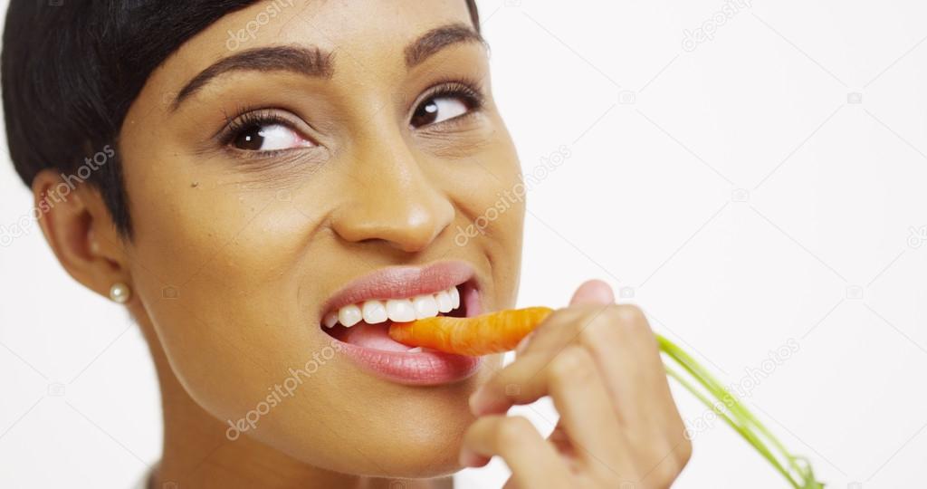 Close up of black woman eating carrot on white background