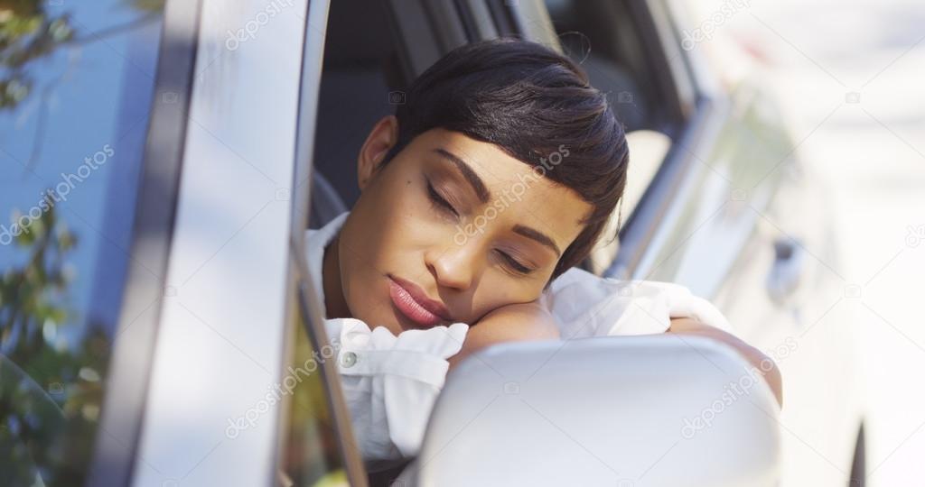 Black woman resting head out car window