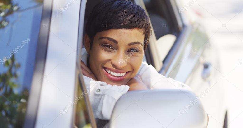 African woman smiling and looking out of car window