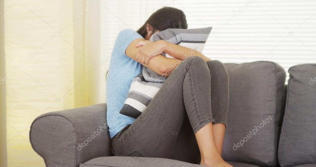 Mixed race woman having a stomachache and hugging pillow