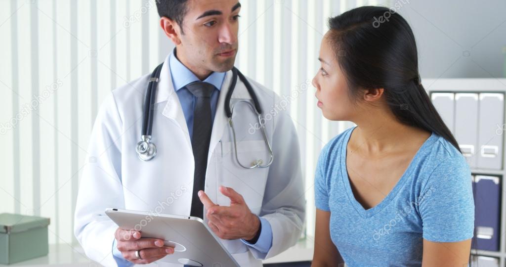 Hispanic doctor talking with patient with test results on tablet