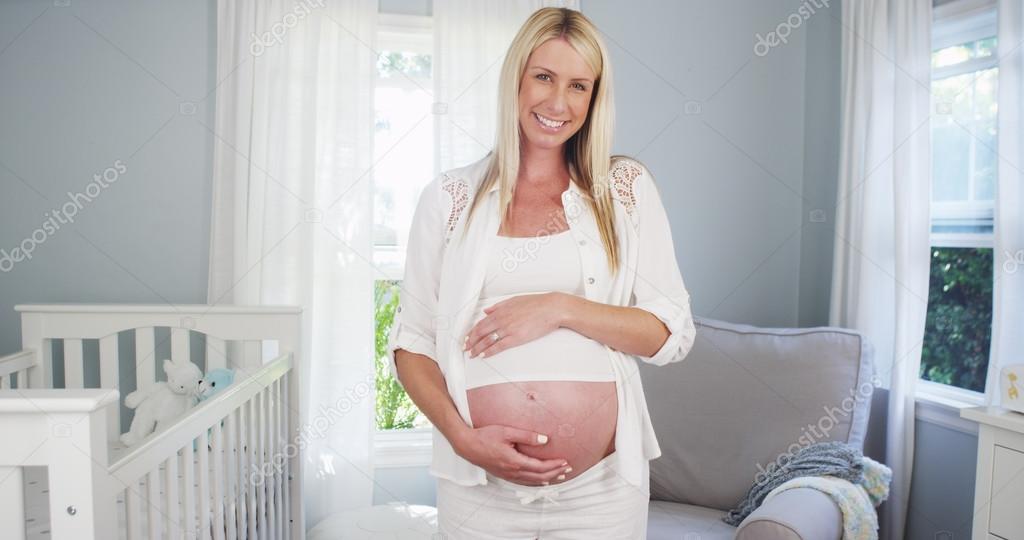 Beautiful pregnant woman standing in nursery
