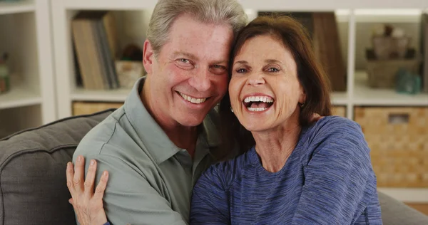 Sweet senior couple cuddling on couch — Stock Photo, Image