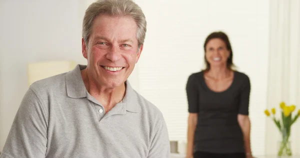 Feliz pareja de ancianos de pie en la sala de estar mirando la cámara — Foto de Stock