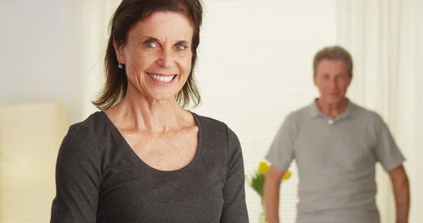 Elderly couple standing in living room smiling — Stock Photo, Image