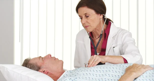 Senior doctor listening to mature patient's heart — Stock Photo, Image