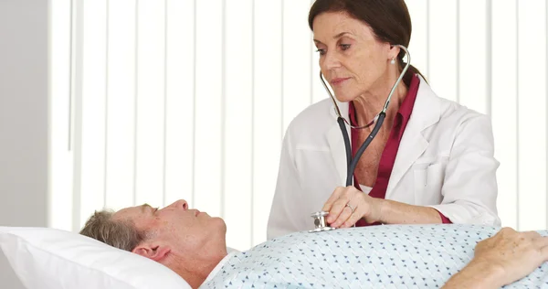 Senior doctor listening to mature patient's heart — Stock Photo, Image