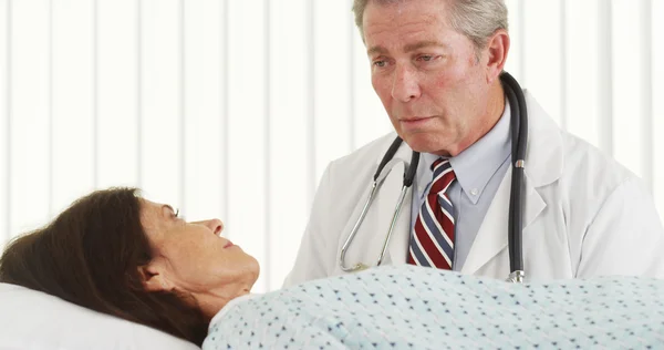 Médico sênior falando e fazendo paciente sorrir — Fotografia de Stock